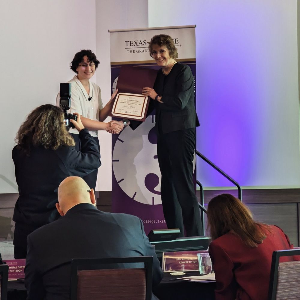 Manar and the dean of the graduate college posing with her finalist certificate.