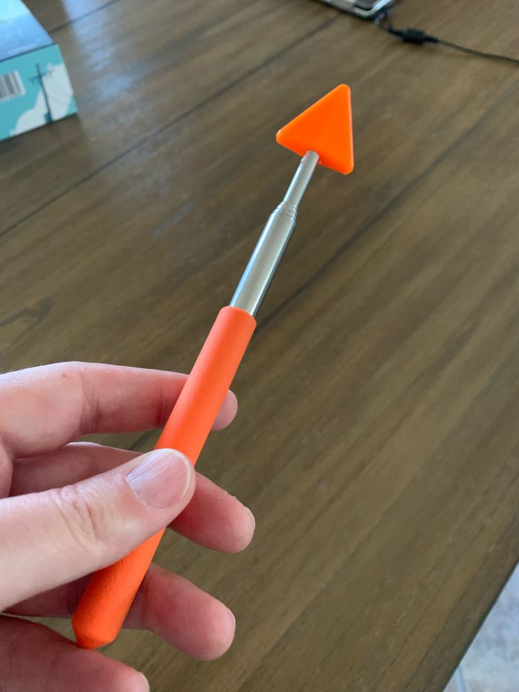 Orange extender pointer wand with orange arrow shaped tip. Useful for pointing out things at a distance across a table