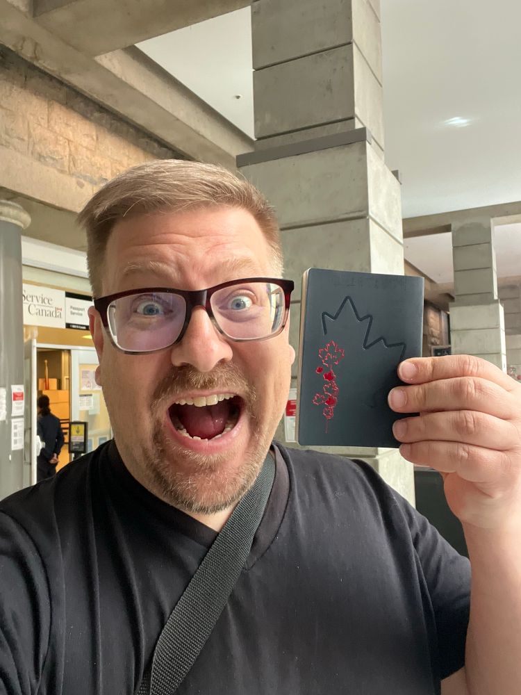 Me in Sinclair Centre outside Service Canada passport office holding up my new passport with the red leaves on the back. 

My mouth is wide open and I have a pleased but crazed look on my face. 