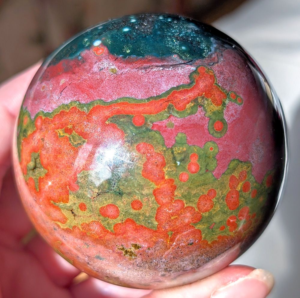 New sphere! I believe it is a variety of ocean jasper. "Ocean Jasper" is formed through the process of silicification, where other minerals are replaced by silica (primarily quartz), resulting in the formation of chalcedony. It primarily consists of silicified rhyolite and quartz. 

