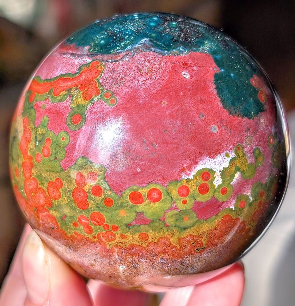 New sphere! I believe it is a variety of ocean jasper. "Ocean Jasper" is formed through the process of silicification, where other minerals are replaced by silica (primarily quartz), resulting in the formation of chalcedony. It primarily consists of silicified rhyolite and quartz. 

