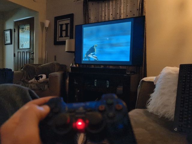 The title sequence for the PS1 game Einhander playing on a TV in the background. PS2 game controller being held in the foreground.