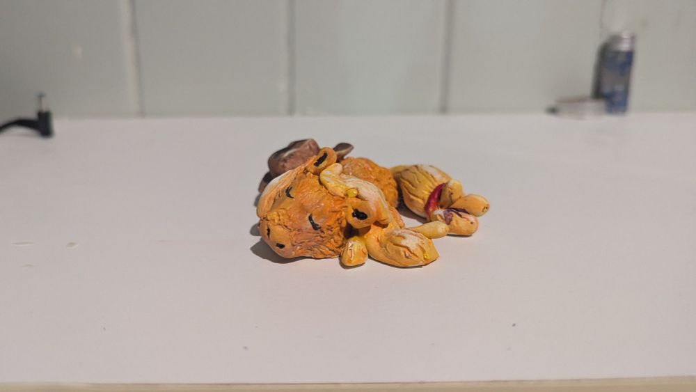 3/4ths view of a stylized Applejack clay figure from the show MLP (My Little Pony) she's laying halfway on her side with her hat on her hind leg