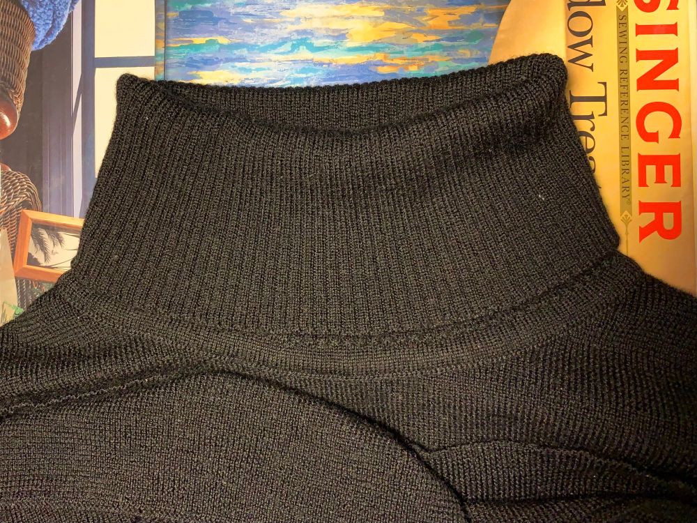A black turtleneck laid flat on a book, with the neck folded over once.