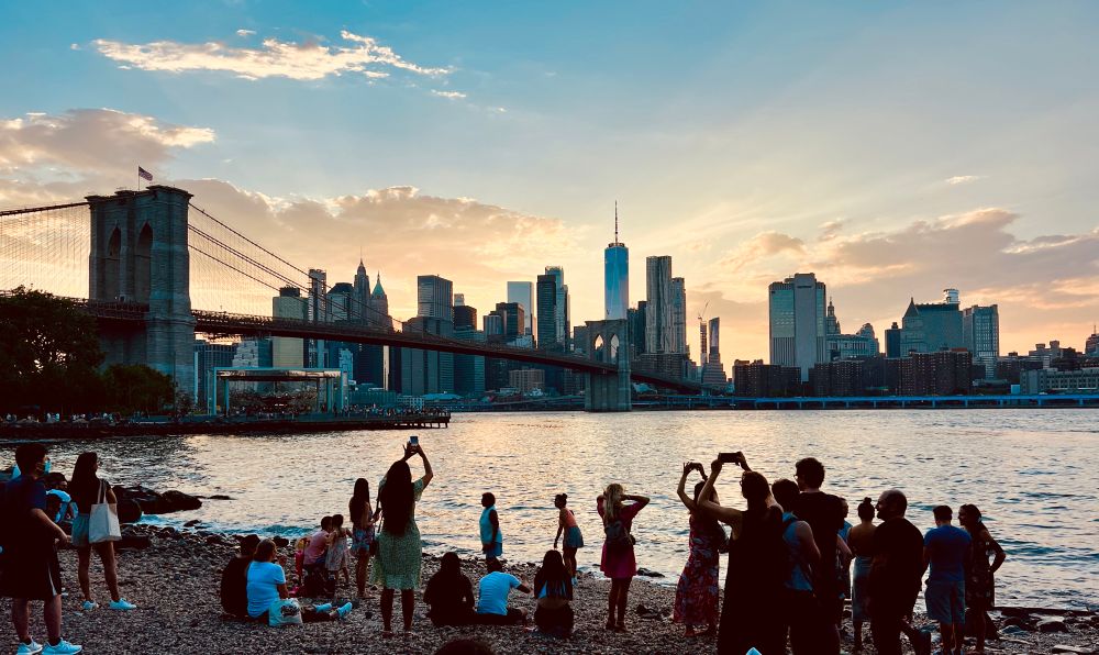 People on Pebble Beach watching the sunset over Manhattan