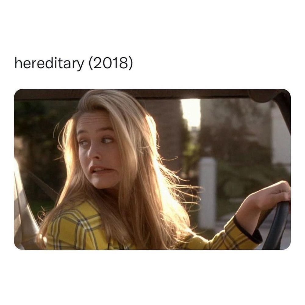 Alicia Silverstone is driving, making a face while turned to look back, like she might've made a mistake trying to parallel park. The caption says "Hereditary (2018)"
