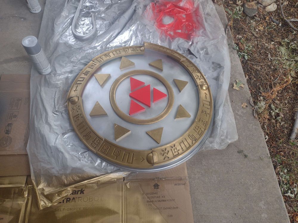 A picture of a shield prop painted but not glued together. The prop is that of Gallantmon from the anime digimon and the shield is a painted sled with 3D printed details 