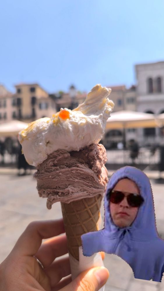 A hand holds up a waffle cone with two generous scoops of gelato. Overlaid is a meme of Damian from Mean Girls with his hood up and sunglasses, a very clever disguise.