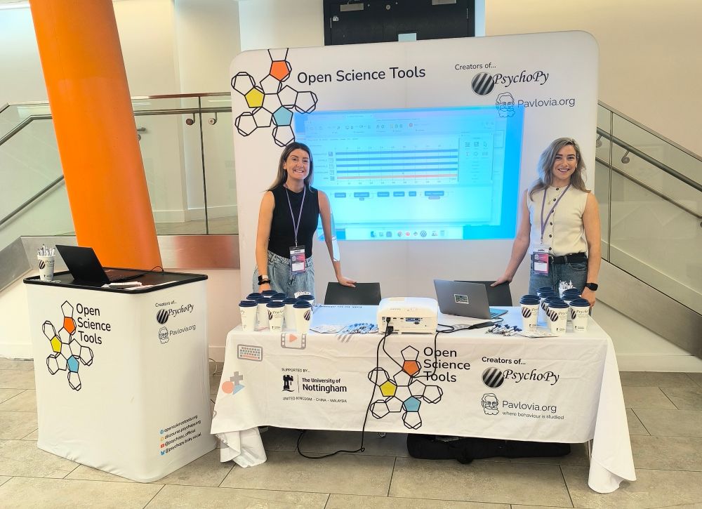 Two happy women stand Infront of an exhibitor booth. Logo reads open science tools. 