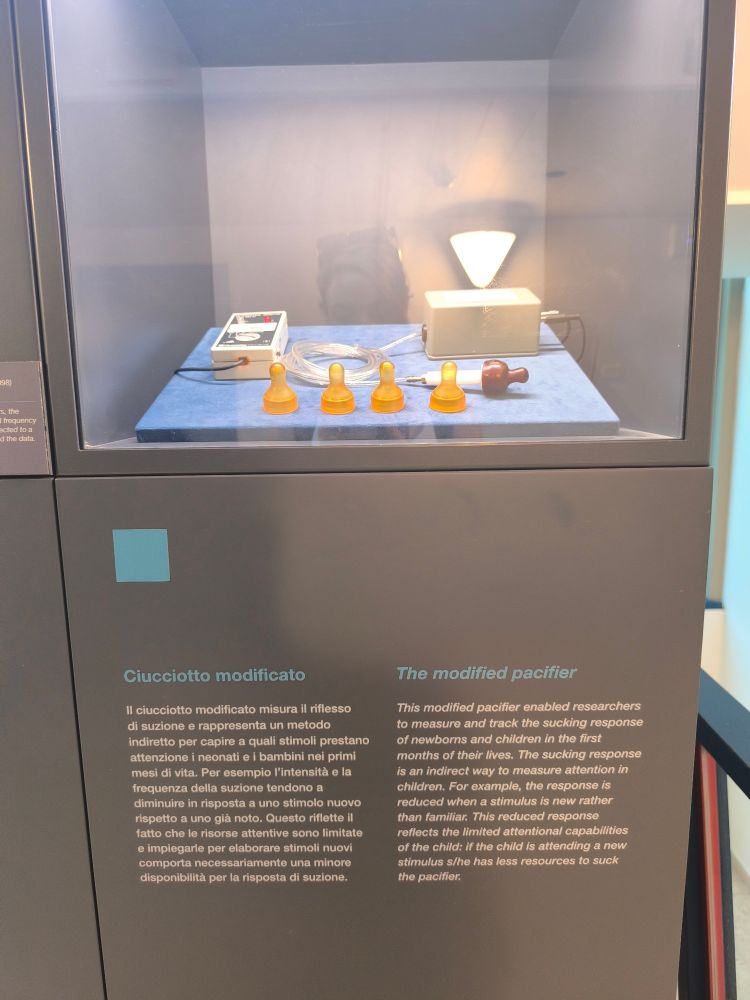 Display shows a number of what appears to be infant bottle tops which can be attached to a tracking device.  The modified pacifier used to measure and track sucking response in infants. The sucking response is an indirect way to measure attention in infants, for example a reduced sucking response is seem when a stimulus is new compared with familiar. 
