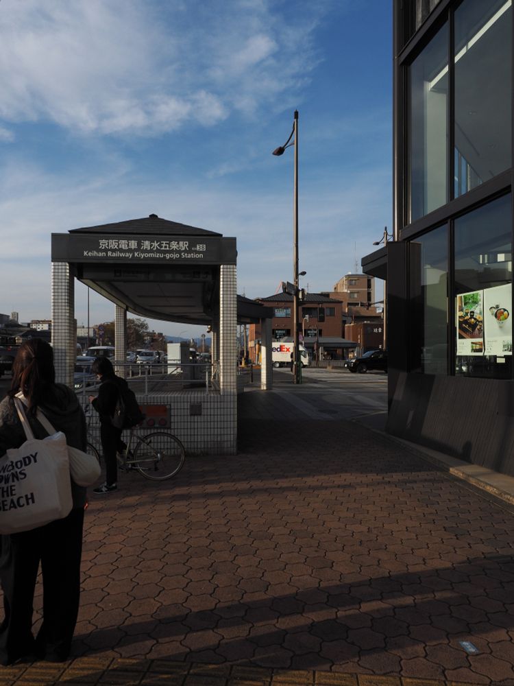歩道と地下駅入口の写真。
茶色くて六角形のレンガ風の舗装の歩道に、歩道幅の半分くらいを占める地下駅への階段の入口がある。
入口の屋根には「京阪電車　清水五条駅　KH38」などと書かれている。