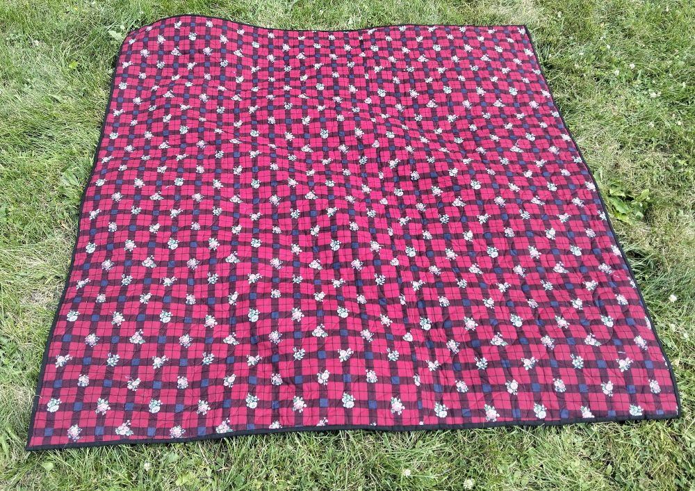 the reverse side of the quilt, it is red with horizontal and vertical bars of dark blue with small white floral shapes on every other bar 