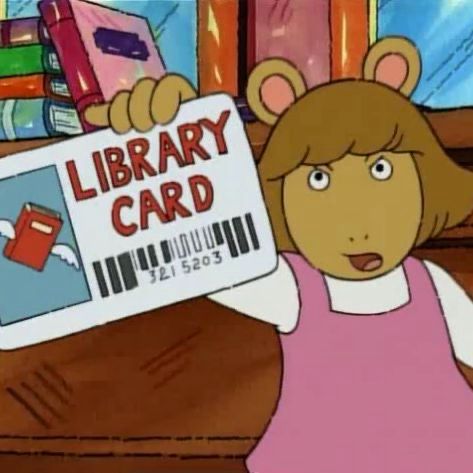 D.W from the cartoon show Arthur. She is an aardvark with a brown bob, and a pink dress with a white long sleeve under the dress. She is holding up a white library card with large red text saying “LIBRARY CARD” 