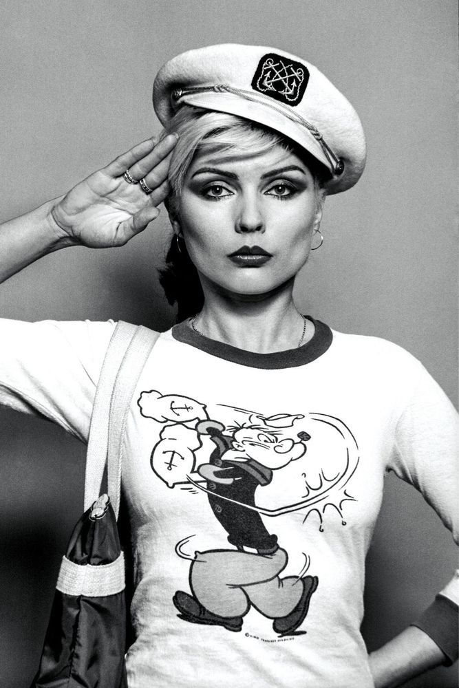 Singer Debbie Harry wearing a Popeye t-shirt. She is saluting those watching.