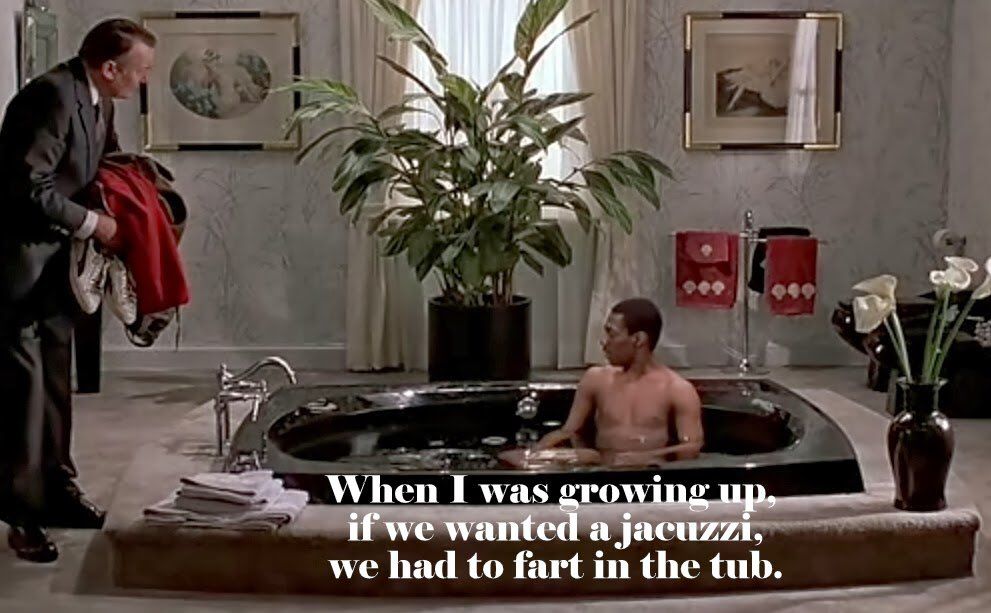 Eddie Murphy sitting in a jacuzzi as his new butler looks on.