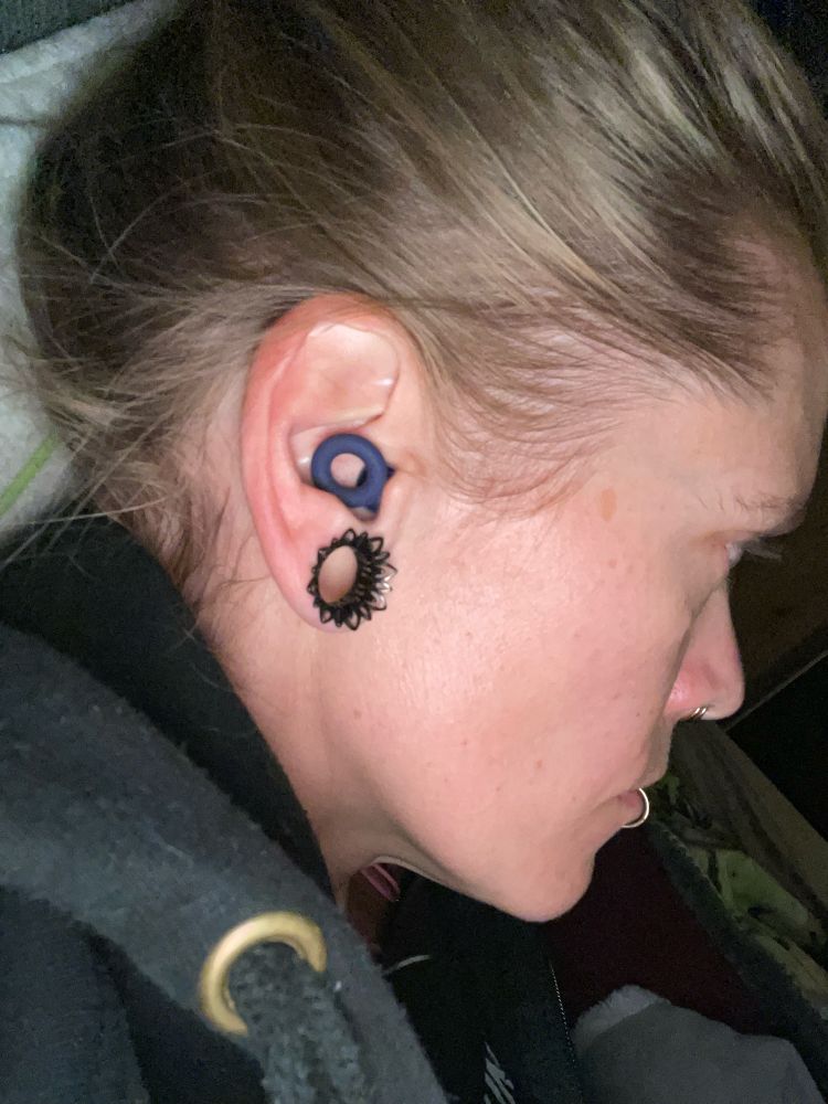 Heppis Profilansicht, im Ohr ein rundes dunkellila Silikonringlein, das zu einem Ohrstöpsel namens Loop earplugs gehört 