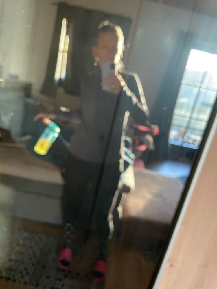 Verschwommenes Spiegelbild von mir in dunklen laufklamotten und pinken Schlappen vor dem Kleiderschrank. Im Hintergrund könnte man das nicht gemachte Bett erkennen, wenn’s nicht so verschwommen wäre. In der Hand halte ich eine hellbraune trinkflasche, in der anderen mein Handy 