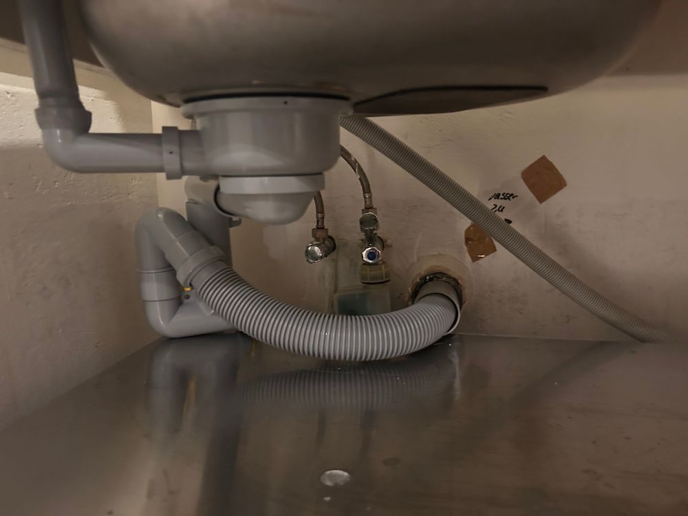 Ansicht unter das Spülbecken mit Blick auf den Siphon. 