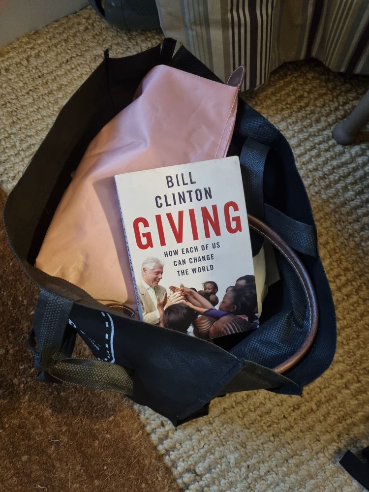 Bill Clinton's book "Giving: How each of us can change the world" in a bag of charity donations