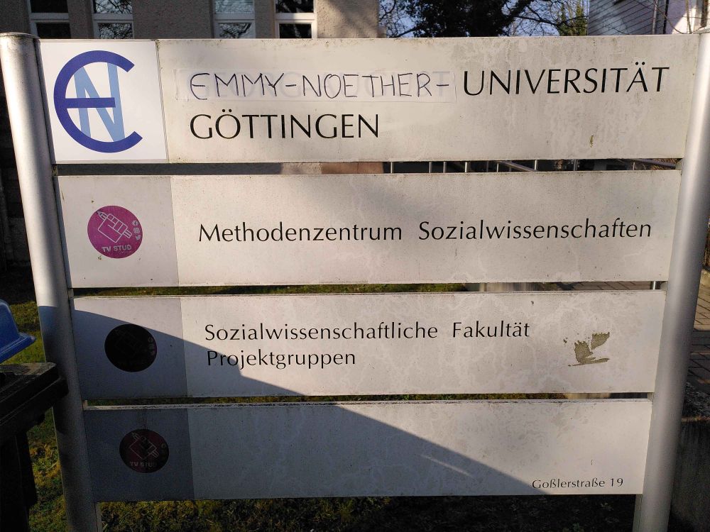 Schild vor dem IMMS Göttingen: Georg-August-Universität überklebt mit Emmy-Noether-Universität