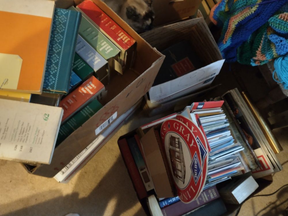 Boxes holding old books, readers digest and maps.