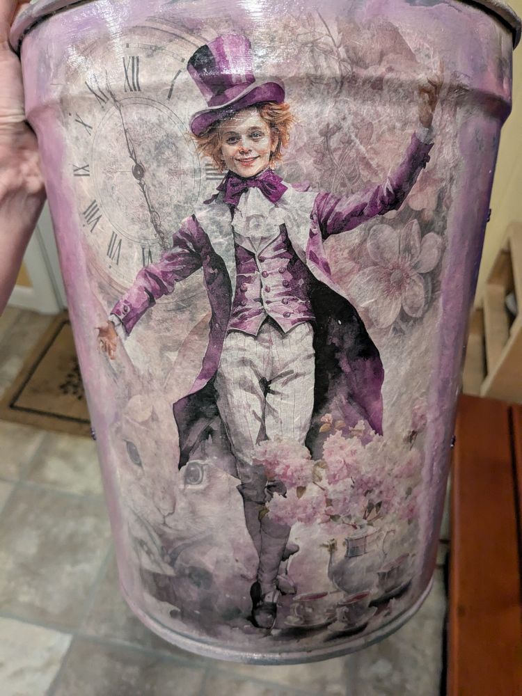 Hand-painted purple metal waste basket with a picture of a clock, and The Mad Hatter on it.