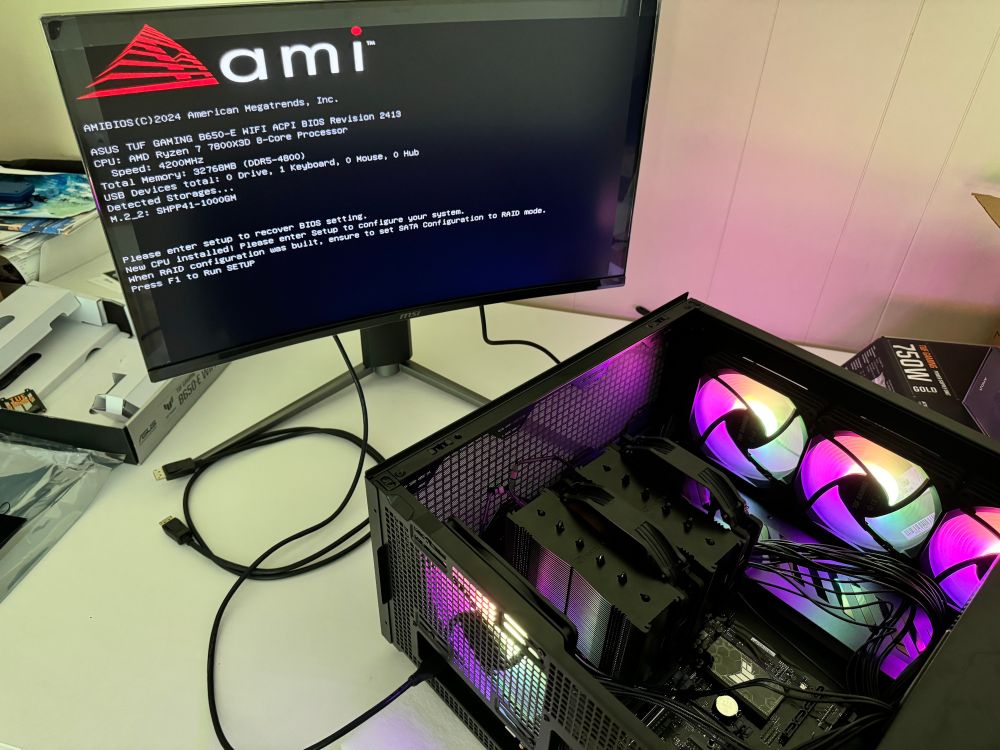 Shua building a computer. Case on side. Everything turned on. Monitor plugged in displaying BIOS booting... Yay, it works!