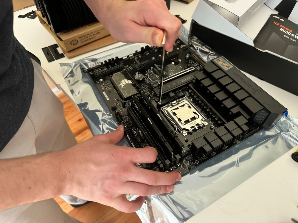 Shua building a computer, screwing in a bracket 