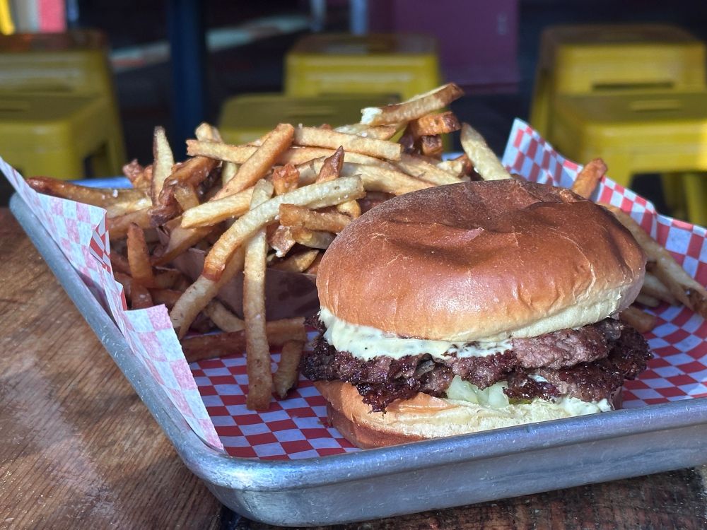 A double smash burger and a side of crispy fries on a tray