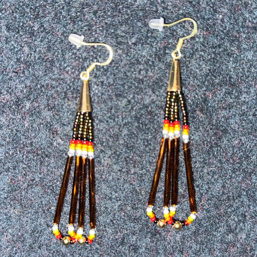 A pair of loop earrings with dark silver, black, red, yellow, and bright silver seed beads, and kind of dark bronze bugle beads topped with a gold cone and hook findings