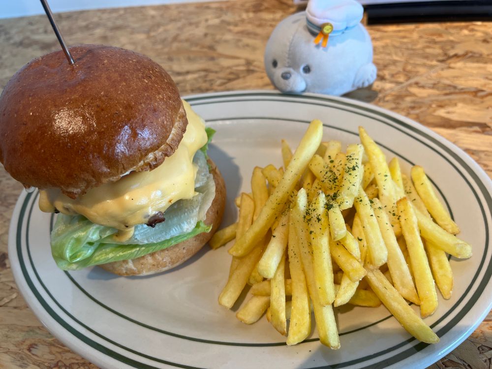 ハンバーガーとポテトのプレートを前にしているアザラシのぬいぐるみ