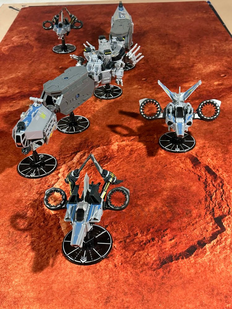 3 toy spaceships flying in formation in front of futuristic train model on Martian terrain 
