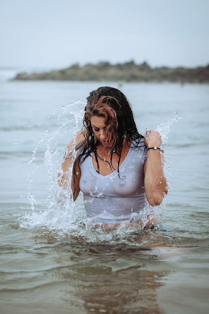 Model in a white tshirt, splashing in the ocean.
