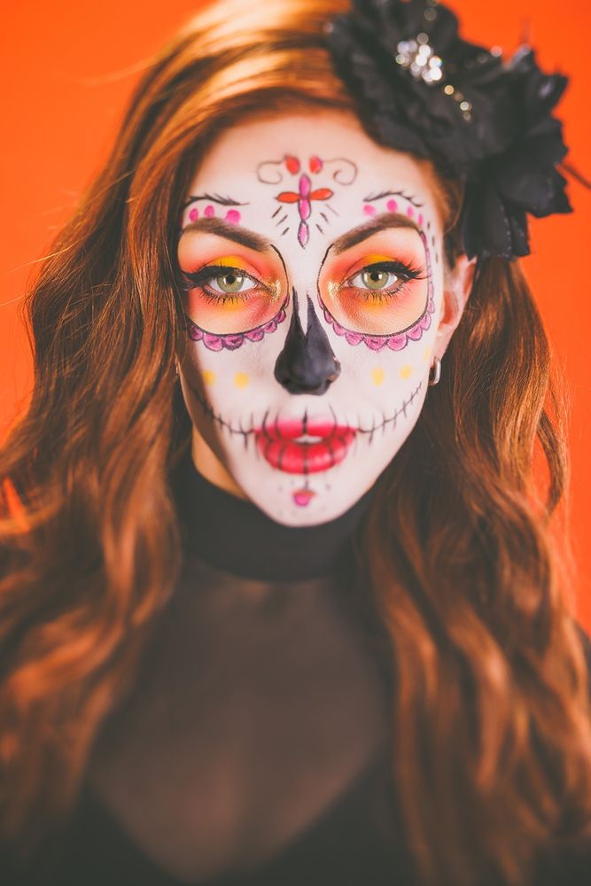 Portrait of a redheaded model in sugar skull makeup and black clothes.  Taken using a Lensbaby Edge 50 lens, producing an image where the eyes are in focus while the rest of the image becomes increasingly out of focus.