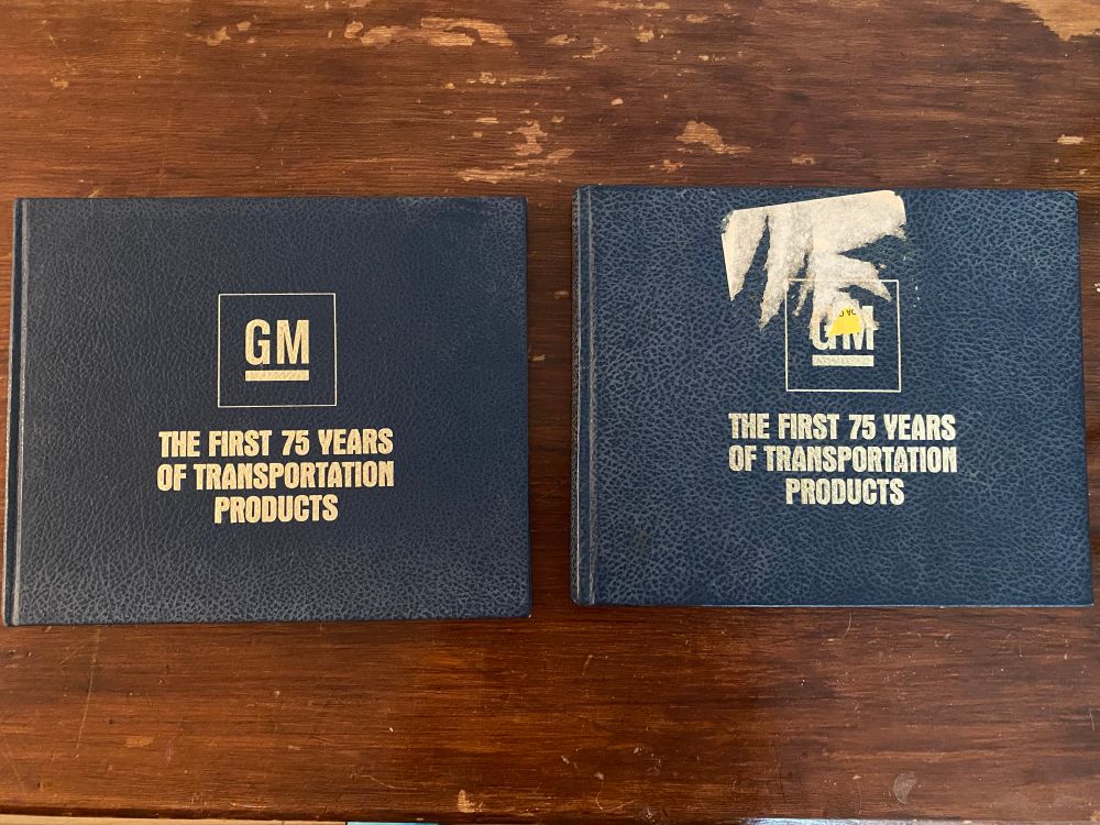 Two books titled “GM The first 75 Years of Transportation Products” one with a sticker scar on the cover. Published in 1983