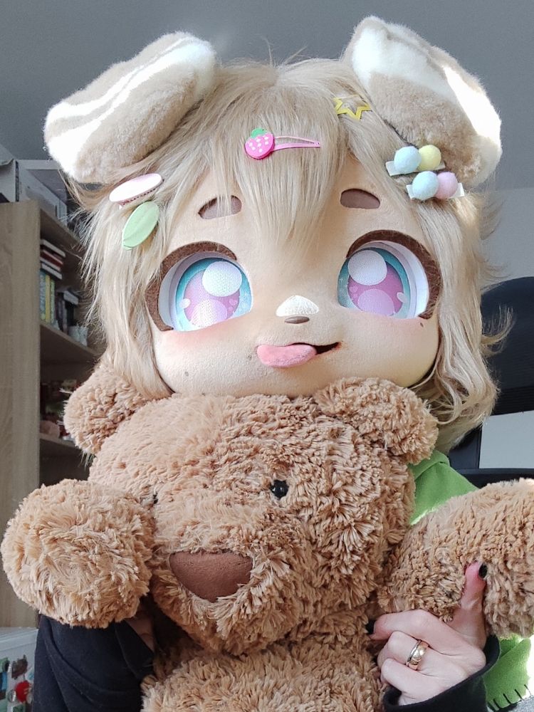 Fursuiter named Basil holding a teddy bear 