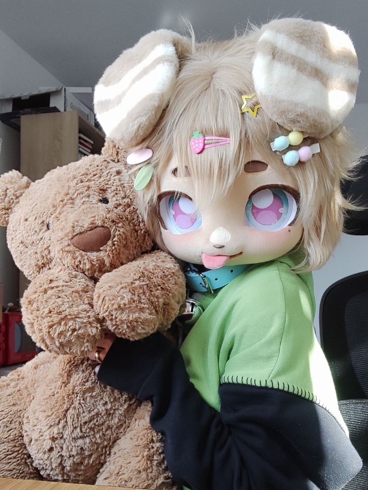 Fursuiter named Basil holding a teddy bear 