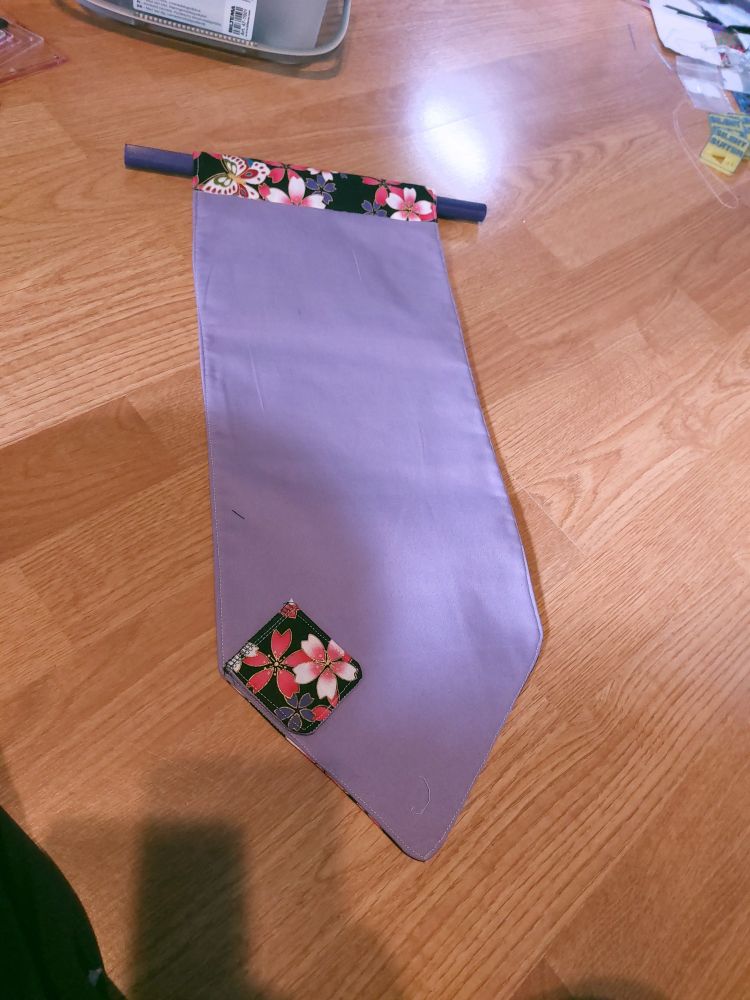 A regular sized pin banner with purple fabric on the frontside. It is approximately 55cm long.