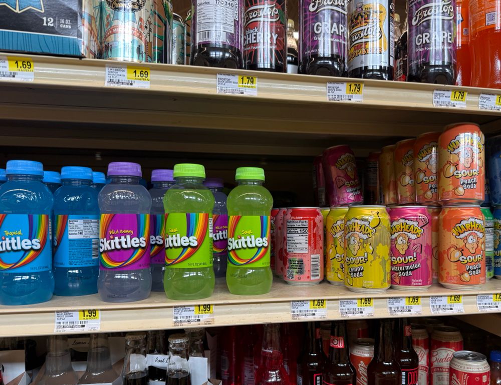 Skittles and Warheads brand sodas on a grocery shelf 