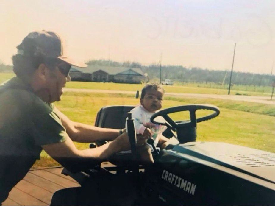 A man placing a baby on a black lawn mower