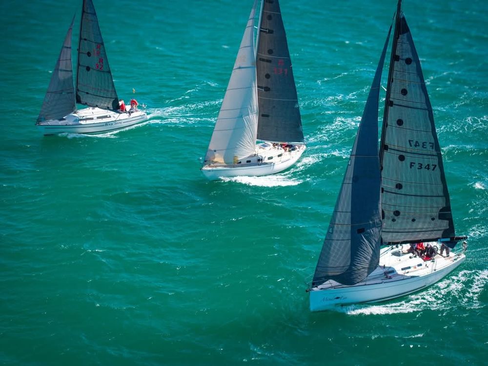 Drone photograph of a front view of three yachts sailing downwind