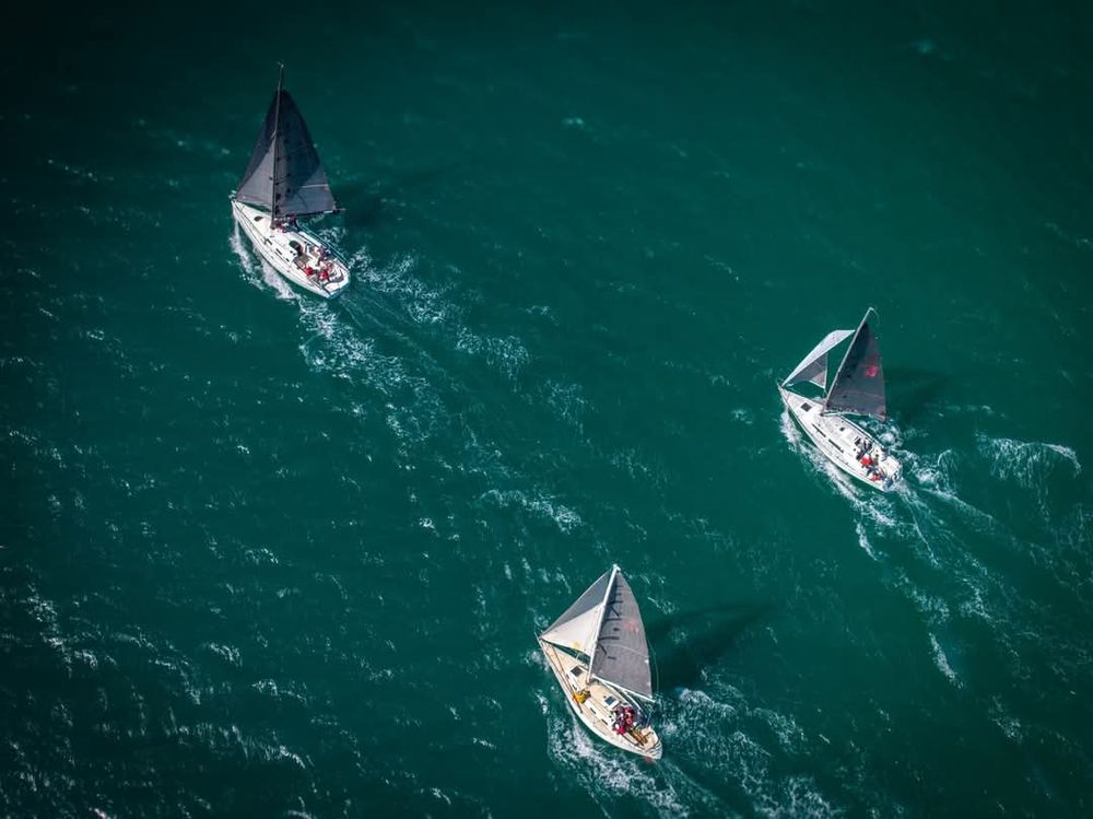 Overhead drone photograph of three yachts sailing downwind.