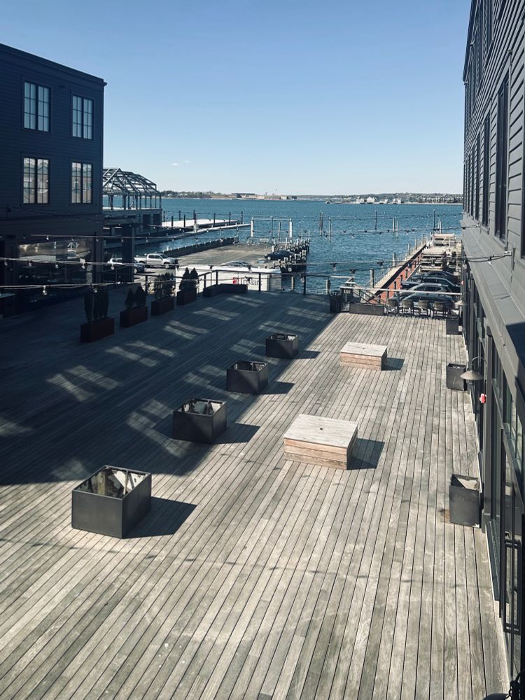 Wide wooden dock flanked by buildings looking out over blue water