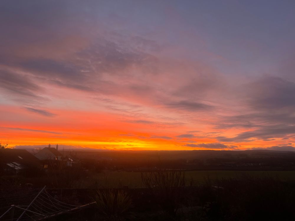The same sunrise but more reds and oranges against the dull early morning sky 