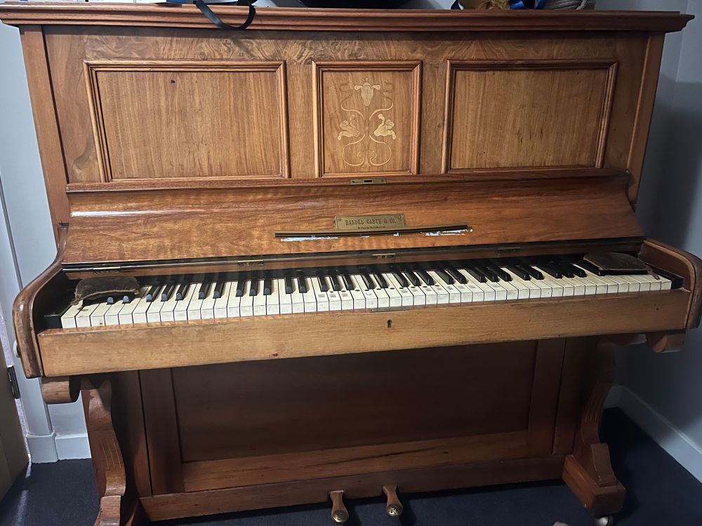 The piano with the lid open and the pretty design in the middle of it, I honestly have no idea how old it is tbh 