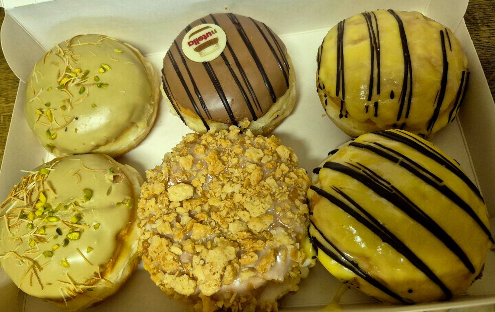 Sechs Berliner in einer Schachtel; zweimal mit Eierlikör, einer mit Nutella, einer mit Bienenstich und zwei mit Pistaziencreme