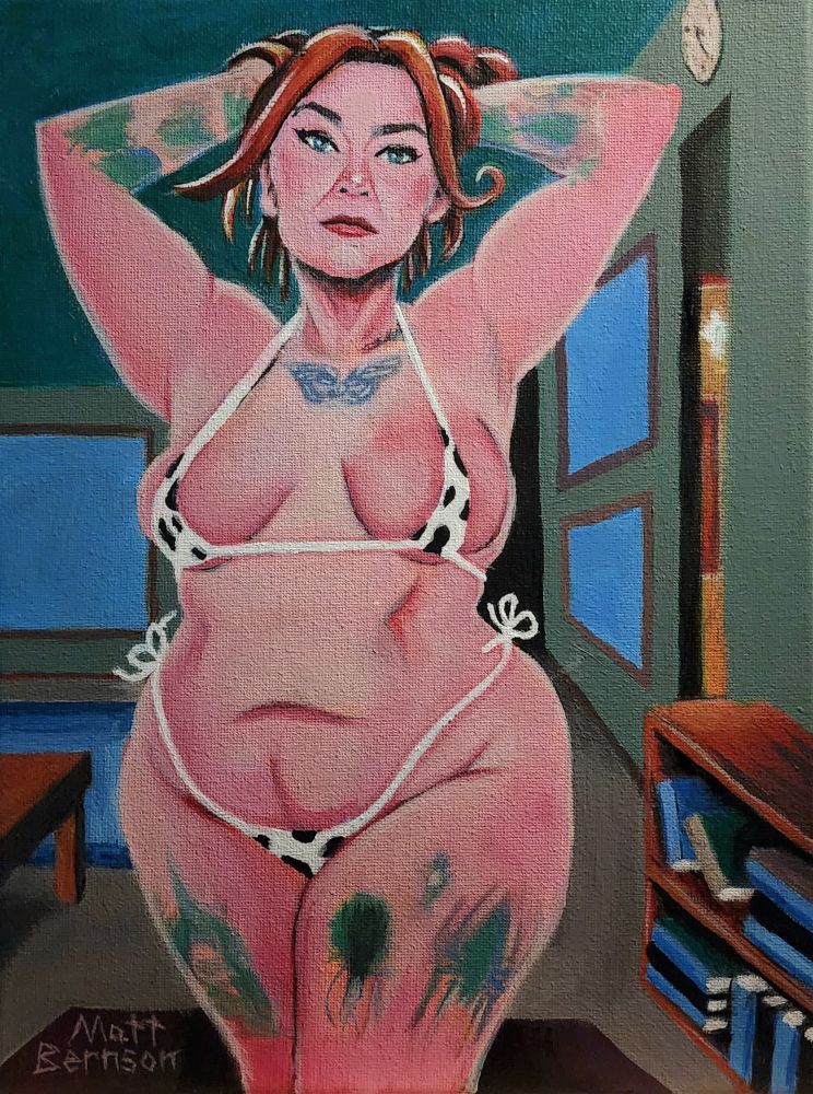 A woman standing in her living room with her hands behind her head. She is wearing a cowprint bikini. 