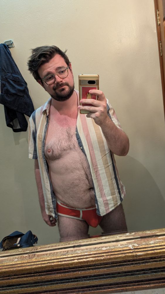 Me posing in the hotel bathroom mirror. Wearing a button up and red briefs. With a sunburn on my neck.