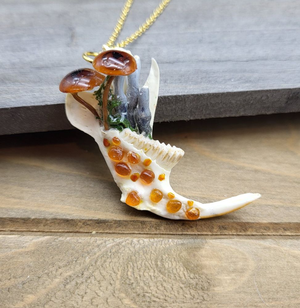 a necklace of hand-sculpted mushrooms on a muskrat jawbone on a golden chain