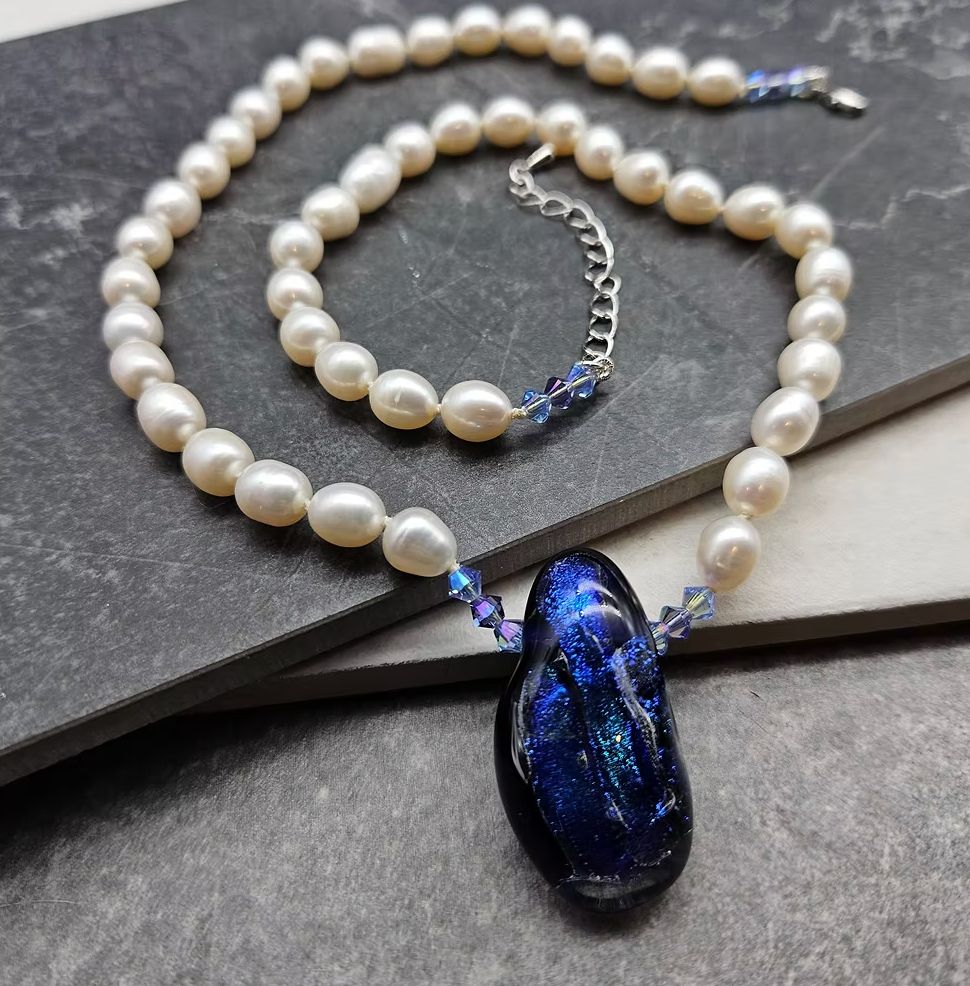 A set of white pearls with a dark blue glass focal. 
